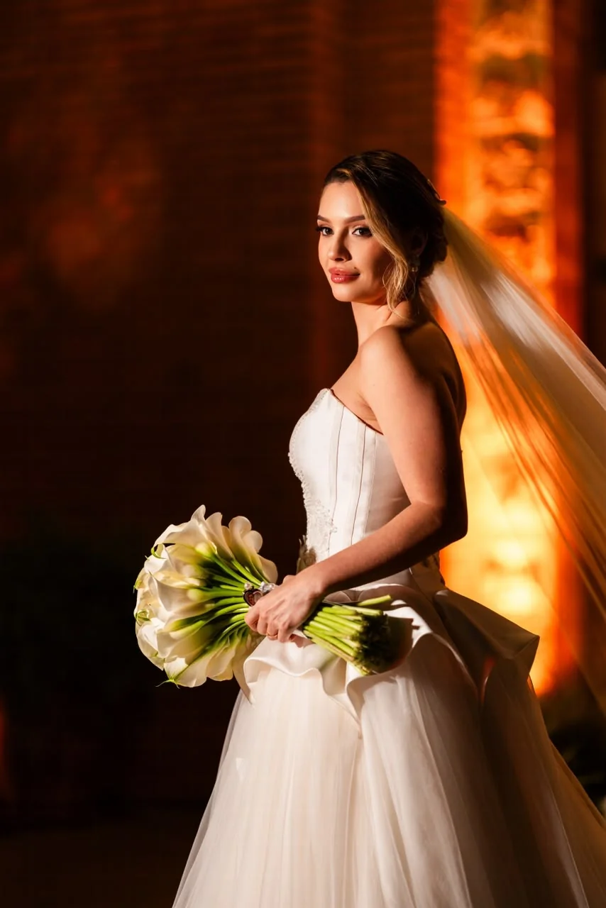 Noiva de perfil com véu e buquê em luz quente